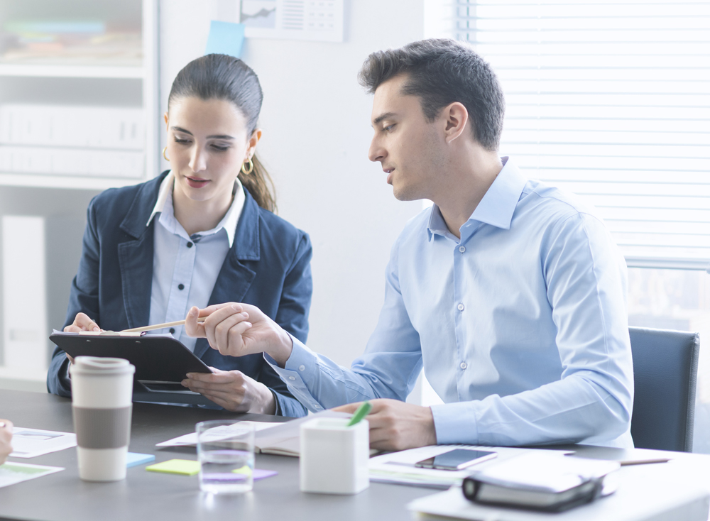 Two adult professionals discussing a document in an office