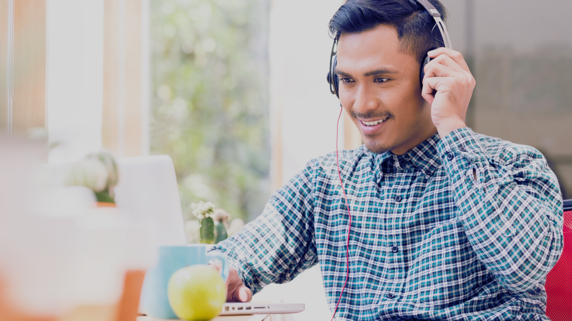 man wearing headphones with microphone looking at computer
